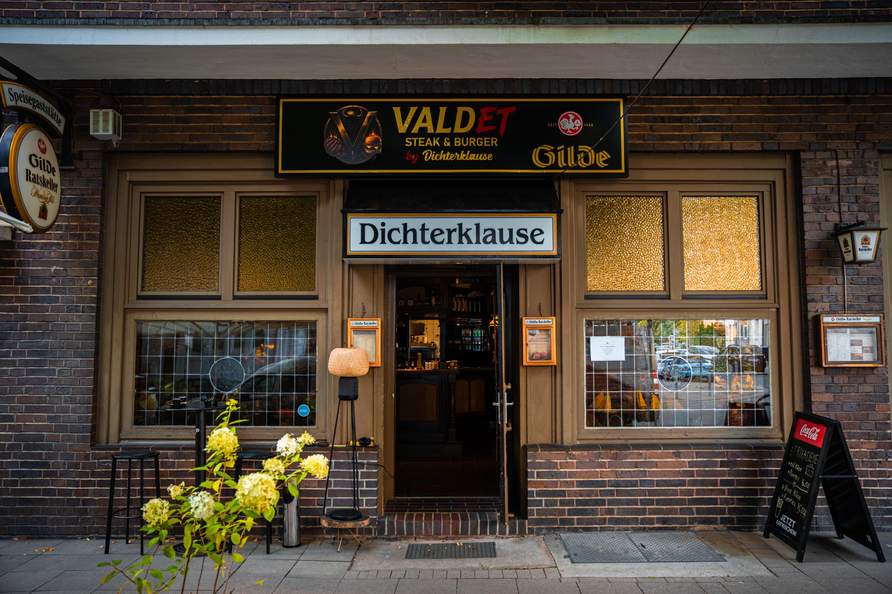 Eingang der Dichterklause mit beleuchtetem VALDET-Schild und Backsteinfassade